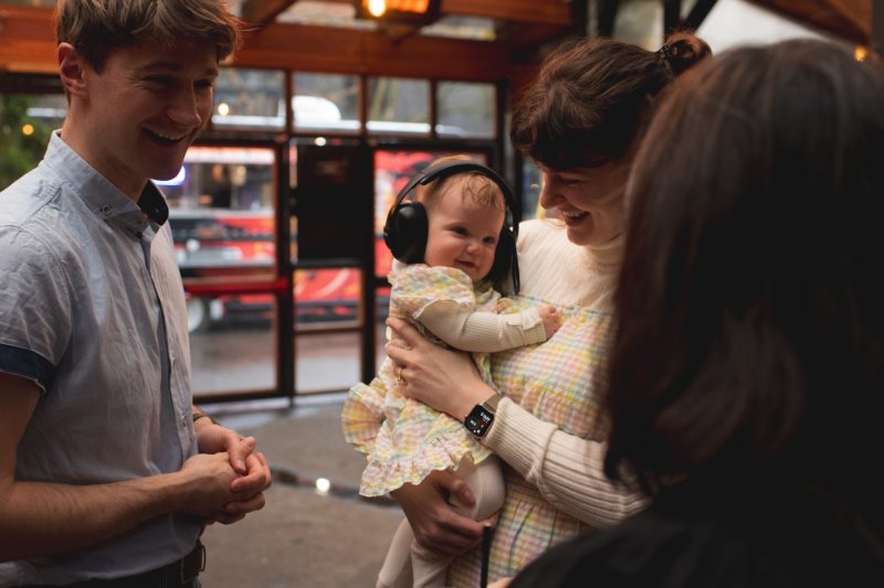 A mother and father smile while the mother holds her baby 